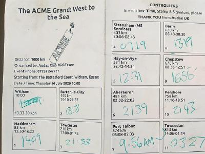 Completed brevet card for ACME Grand cycling event showing 12 control points with handwritten arrival/departure times in green ink, distance totals per section, and contact details for Audax UK.